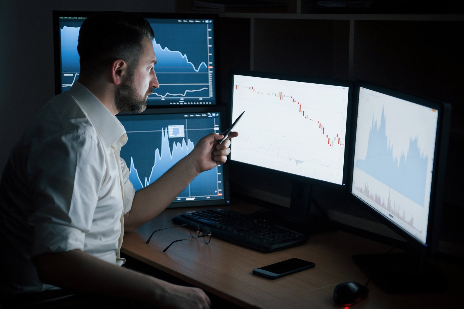 Analyst studying stock market data across monitors